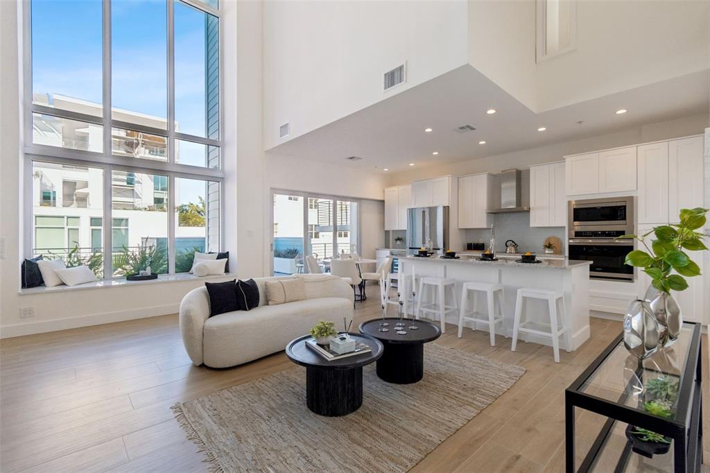 An elevated view of an open-concept living room and kitchen with light wood flooring — 1343 4TH STREET UNIT 202, SARASOTA, FL