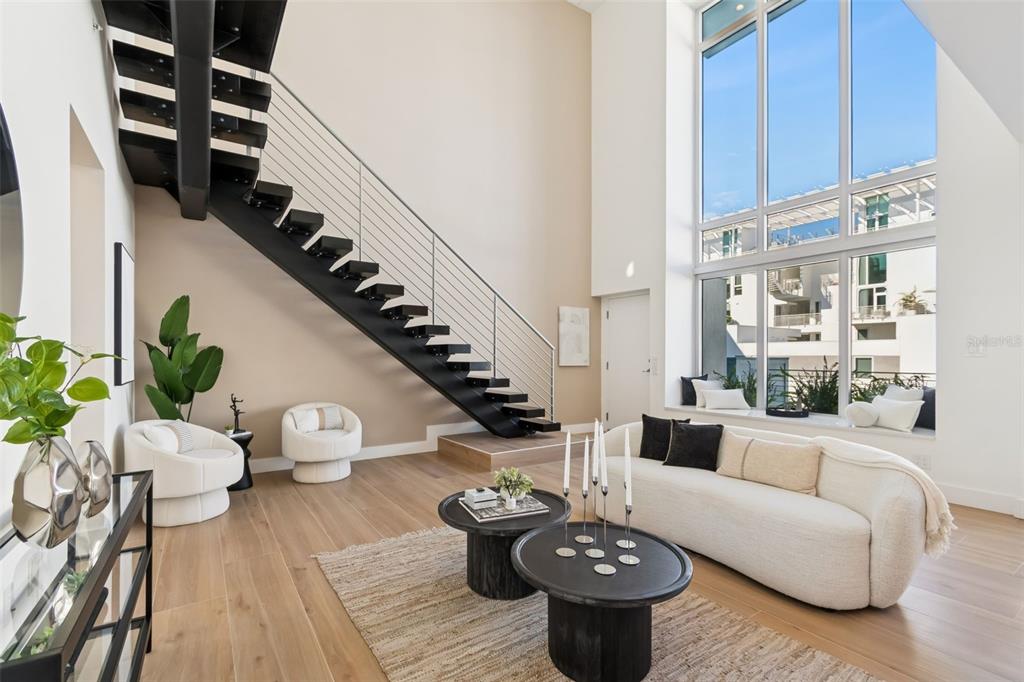A living room features a curved sofa, a wooden coffee table, and large floor-to-ceiling windows — 1343 4TH STREET UNIT 202, SARASOTA, FL