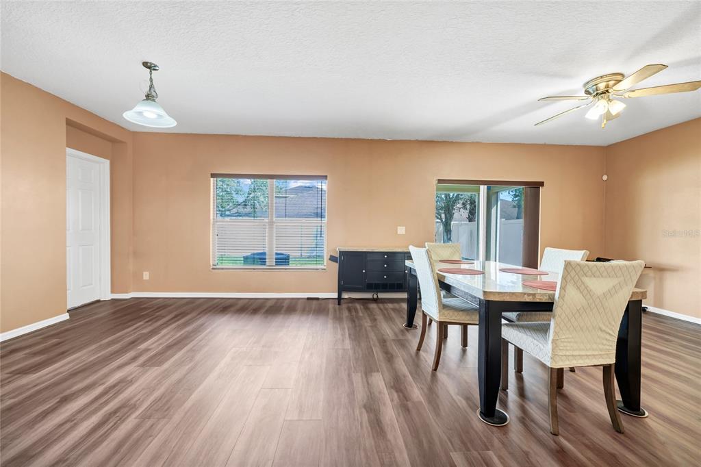 A dining room with wood-look flooring, a table with chairs, and a ceiling fan — 4607 KALISPELL ROAD, KISSIMMEE, FL