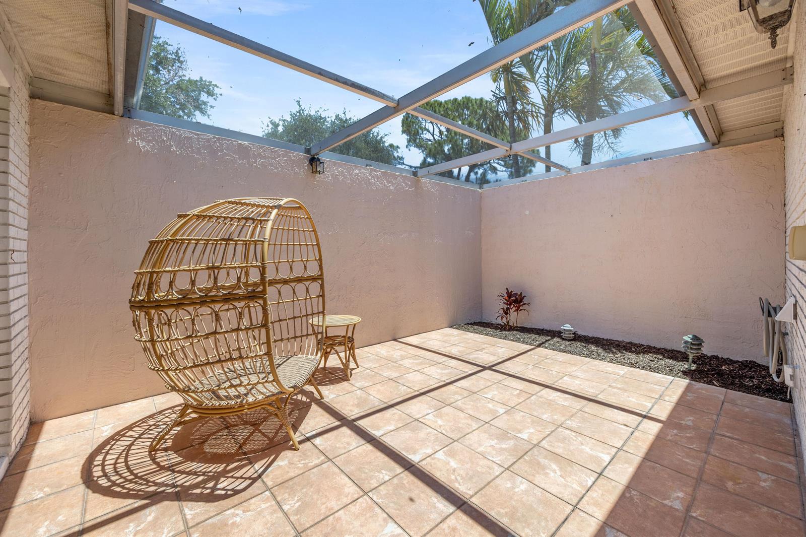 A screened-in patio features light-colored tile flooring, a wicker egg chair, and a small table — 10168 43rd Trail S # 318, Boynton Beach FL 33436, BOYNTON BEACH, FL