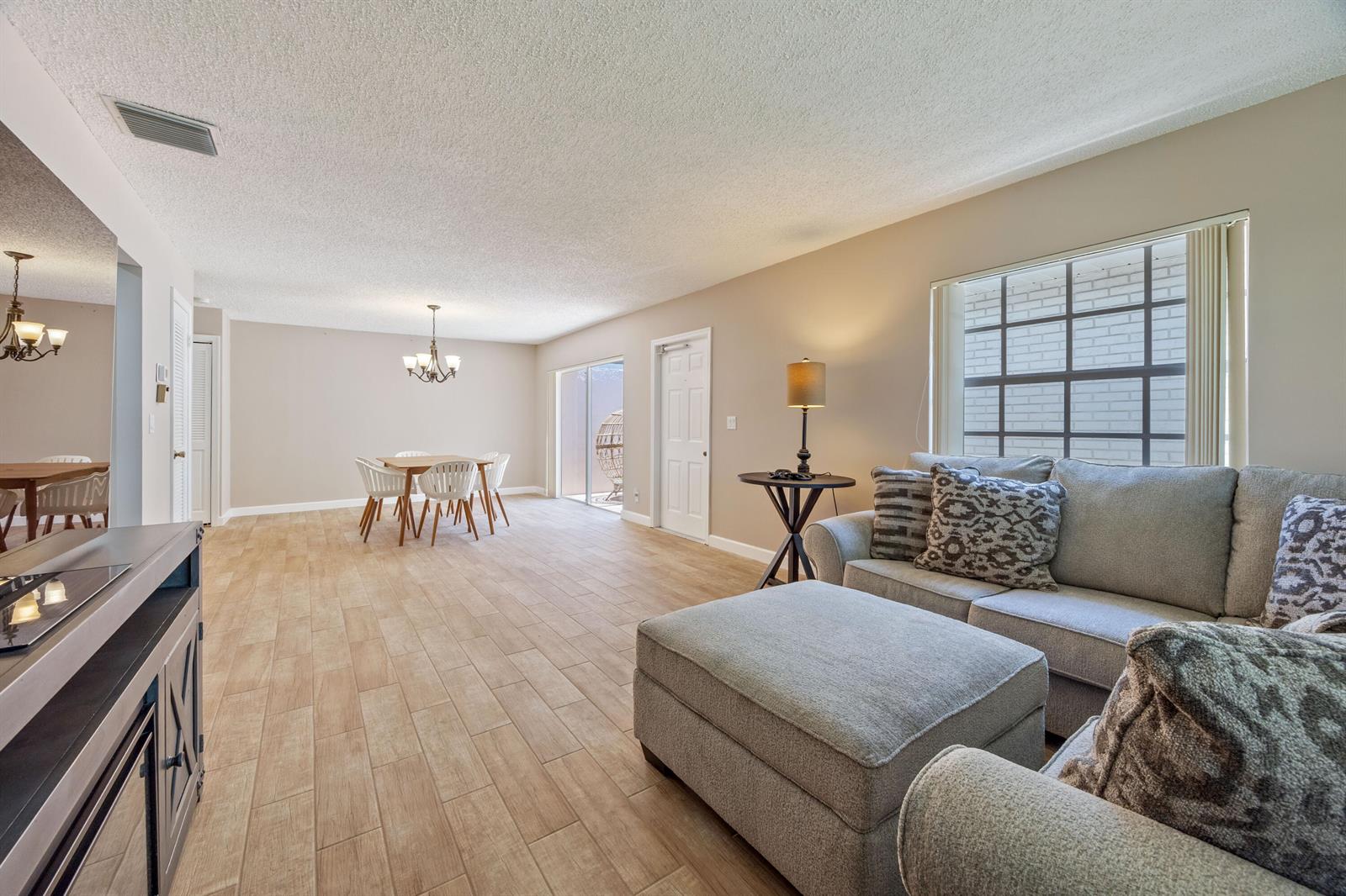 An open-concept living and dining area features light wood-look tile flooring and neutral walls — 10168 43rd Trail S # 318, Boynton Beach FL 33436, BOYNTON BEACH, FL
