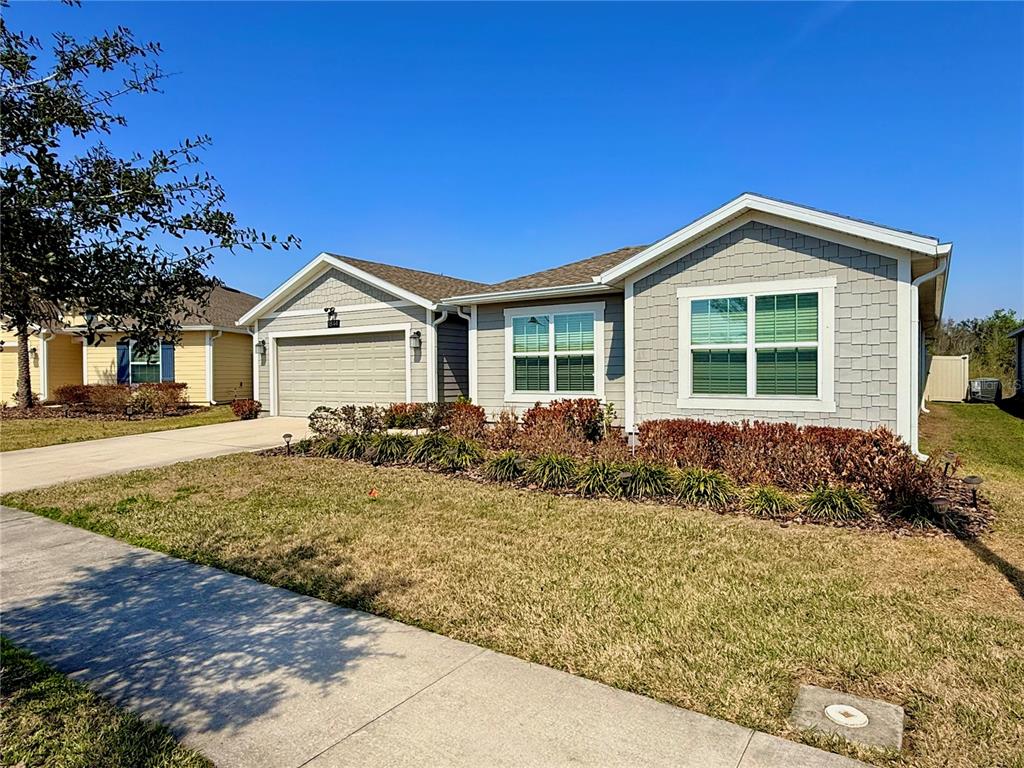 A single-story suburban house with a two-car garage, gray siding, and a landscaped front yard — 1844 ANCESTRY TRAIL, KISSIMMEE, FL