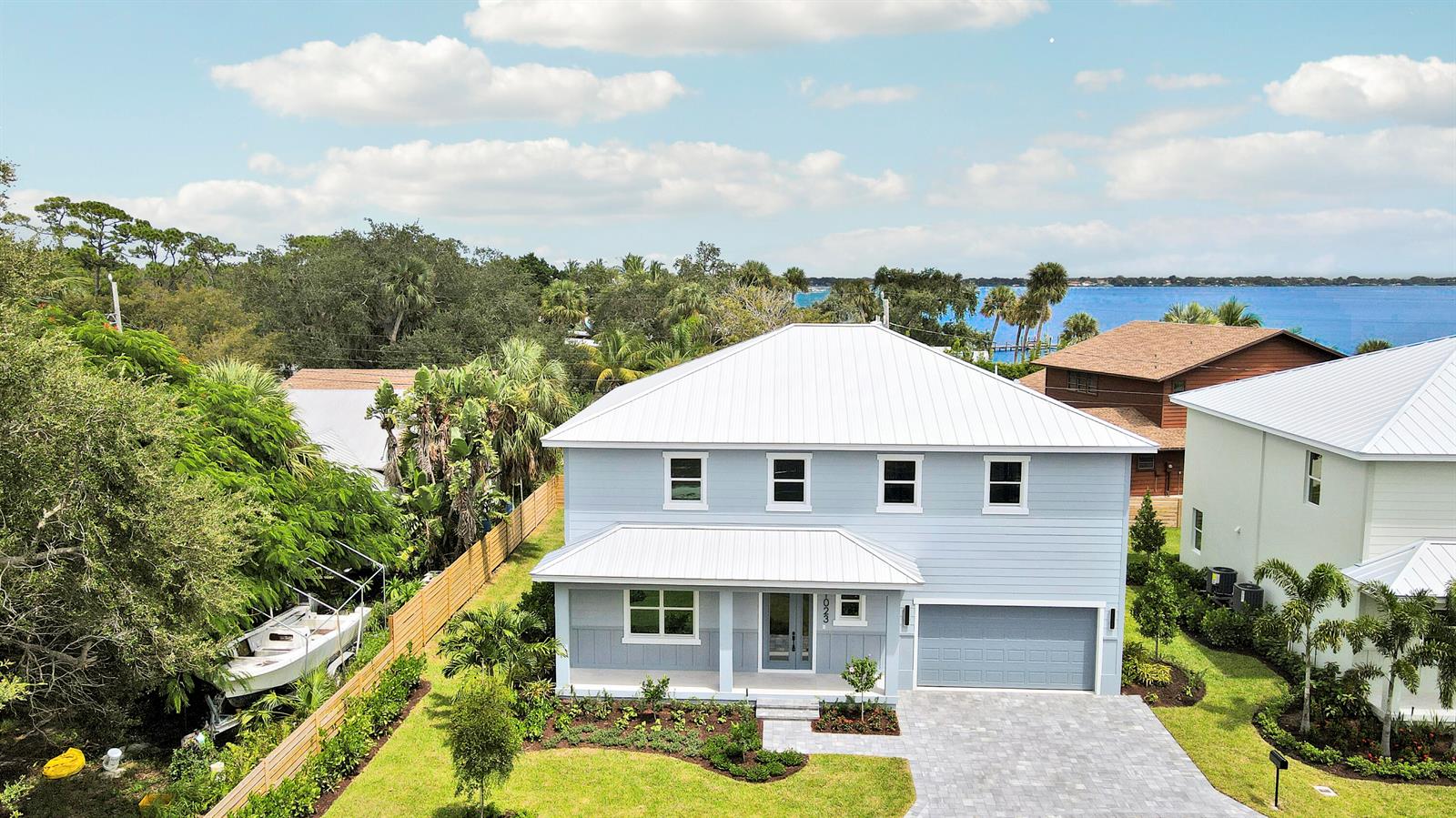 An aerial view of a light blue two-story house with a white metal roof — 1023 NE Orange Avenue, Jensen Beach FL 34957, JENSEN BEACH, FL