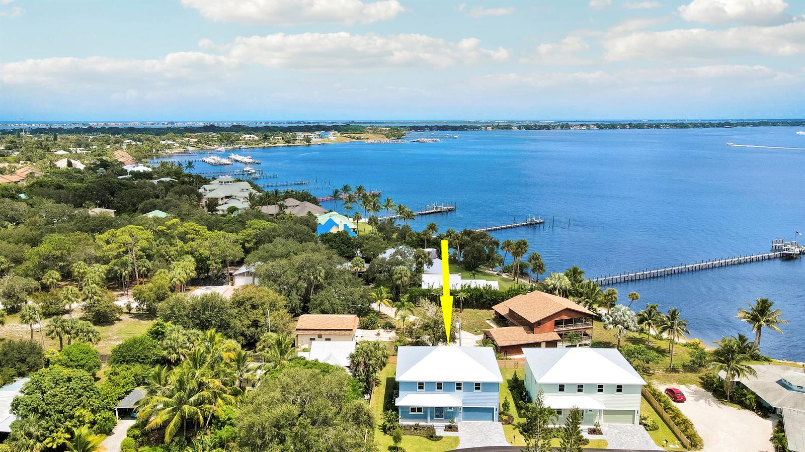 An aerial view shows a blue two-story house near a large body of water — 1023 NE Orange Avenue, Jensen Beach FL 34957, JENSEN BEACH, FL