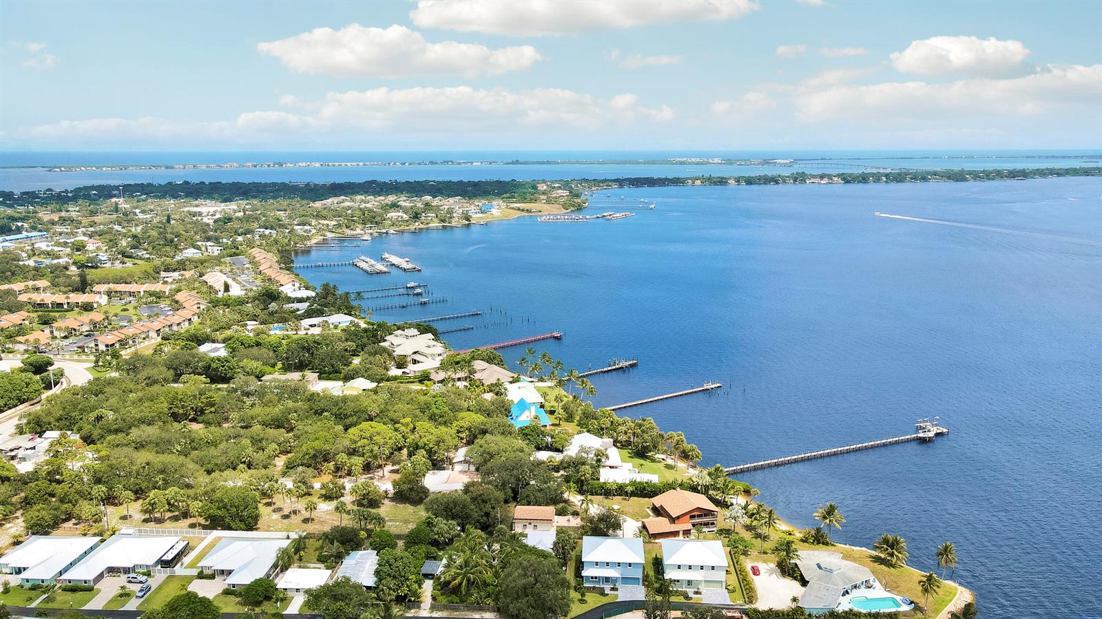 An aerial view shows waterfront homes with private docks extending into a large bay — 1023 NE Orange Avenue, Jensen Beach FL 34957, JENSEN BEACH, FL