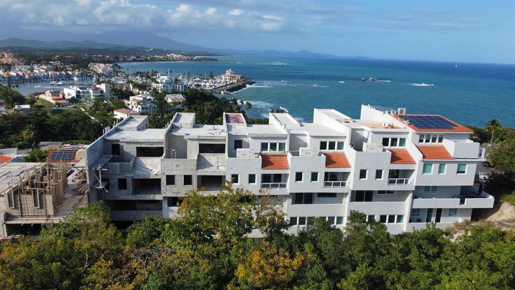 An aerial view shows a multi-story residential building under construction overlooking a coastal harbor — . SHELL CASTLE CLUB UNIT 46, HUMACAO, PR