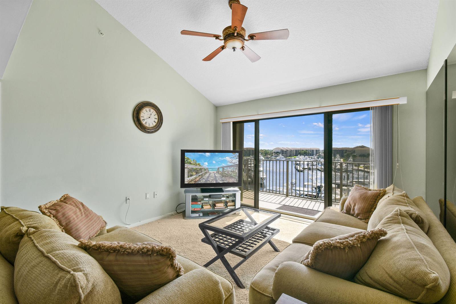 A living room with two beige sofas, a glass coffee table, and a balcony view — 1601 Marina Isle Way # 505, Jupiter FL 33477, JUPITER, FL