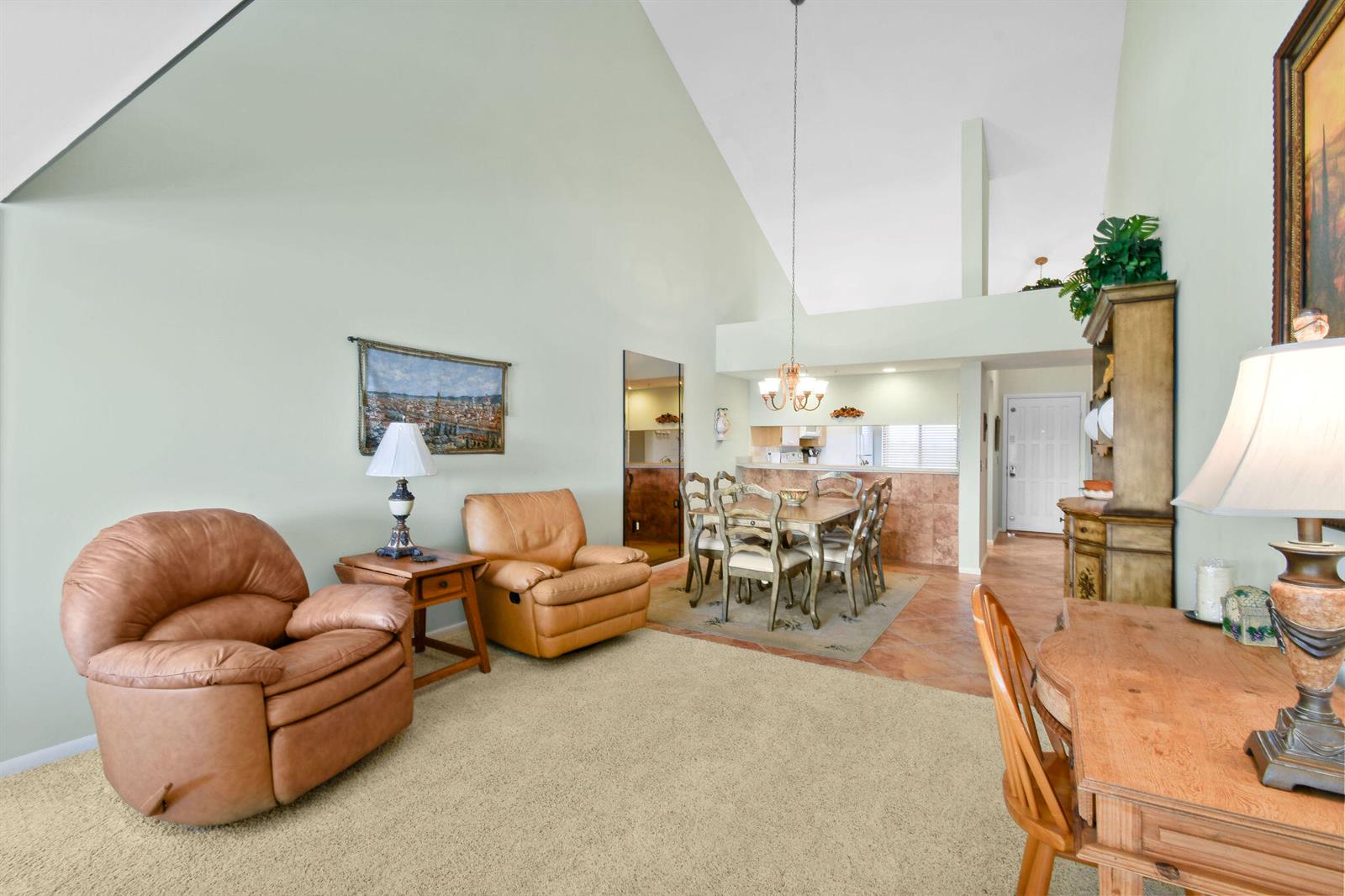 A living and dining area features vaulted ceilings, tan carpet, tile flooring, and leather recliners — 1601 Marina Isle Way # 505, Jupiter FL 33477, JUPITER, FL