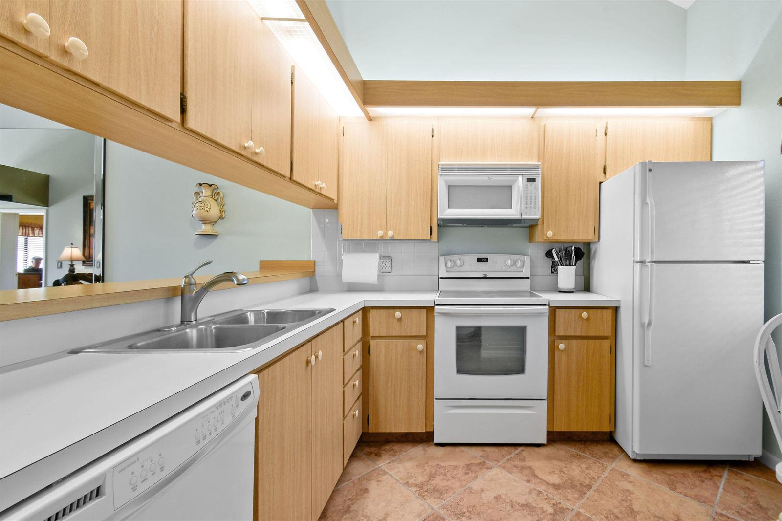 A kitchen features light wood cabinets, white appliances, a double sink, and tiled flooring — 1601 Marina Isle Way # 505, Jupiter FL 33477, JUPITER, FL