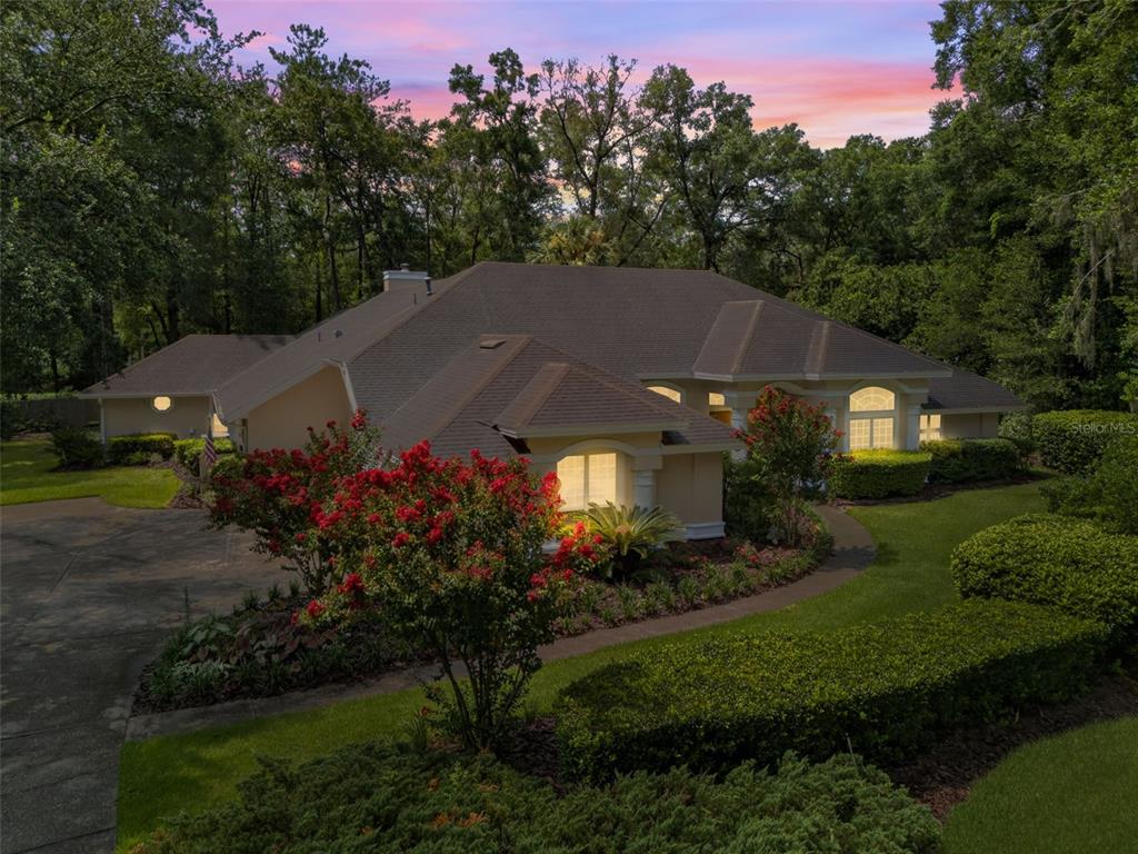 A single-story house with a beige exterior, a dark shingled roof, and landscaped front gardens — 9227 SW 43RD LANE, GAINESVILLE, FL