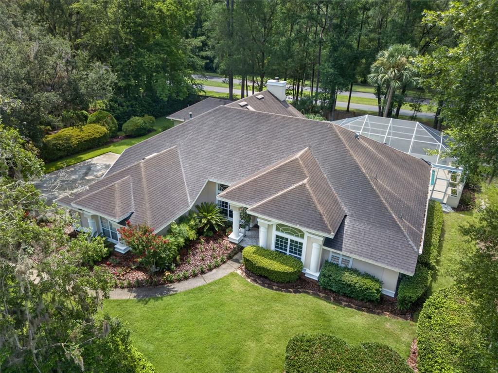 An aerial view of a single-story house with a shingled roof and a screened pool — 9227 SW 43RD LANE, GAINESVILLE, FL