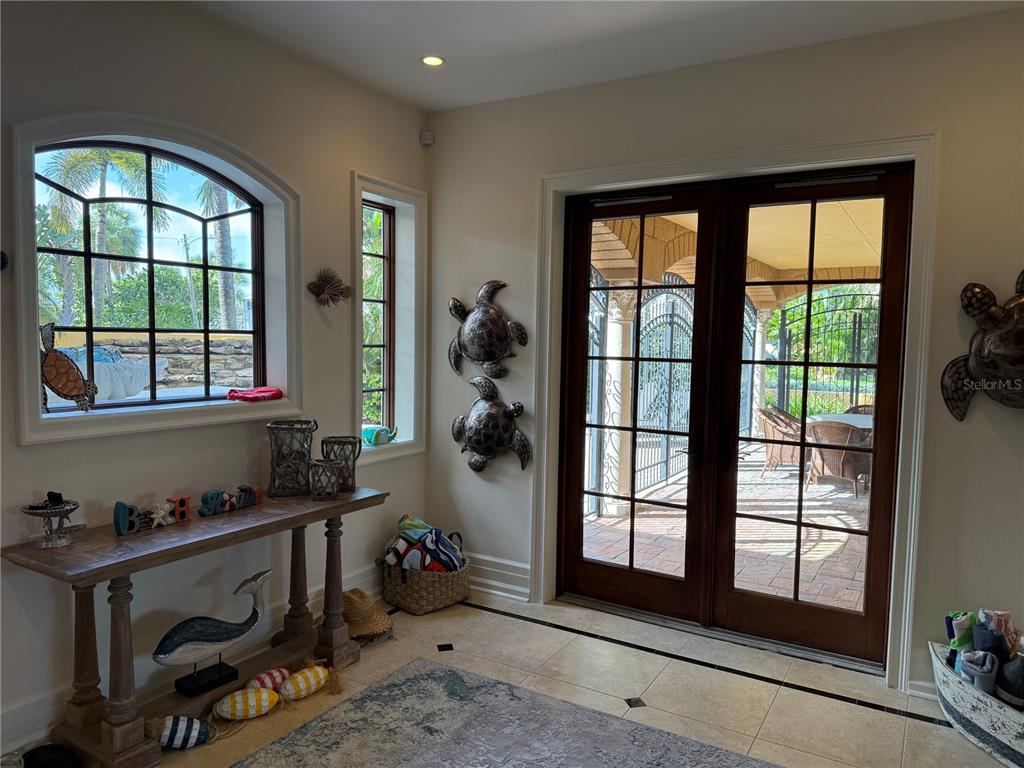 A sunlit entryway features tile floors, a wooden console table, and French doors leading outside — 829 BRUCE AVENUE, CLEARWATER BEACH, FL