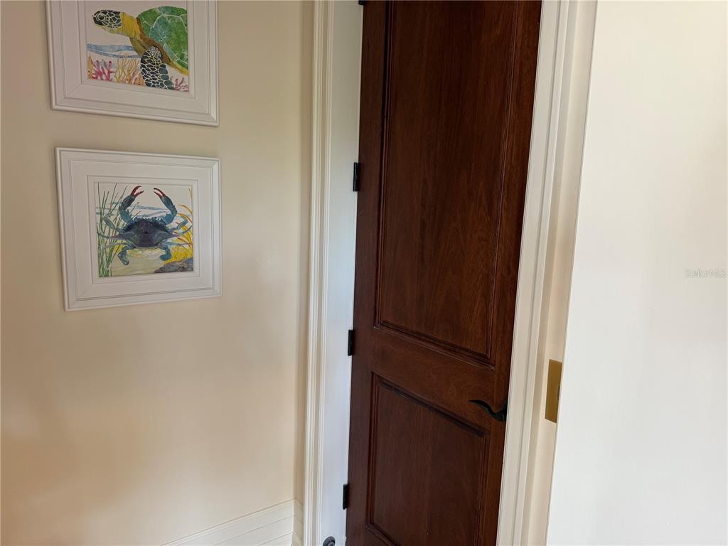 A dark wood door stands next to a wall decorated with two framed coastal prints — 829 BRUCE AVENUE, CLEARWATER BEACH, FL