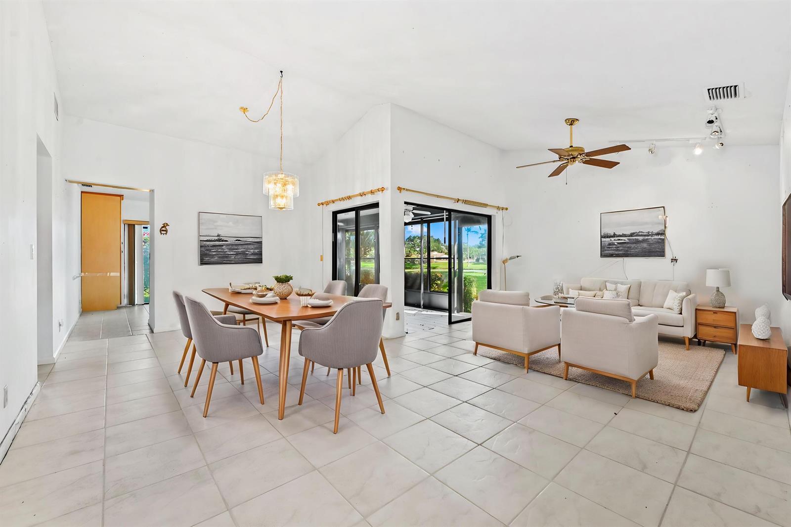 An open-concept living and dining area features white walls, tile flooring, and sliding glass doors — 5537 Parkwalk Circle E, Boynton Beach FL 33472, BOYNTON BEACH, FL