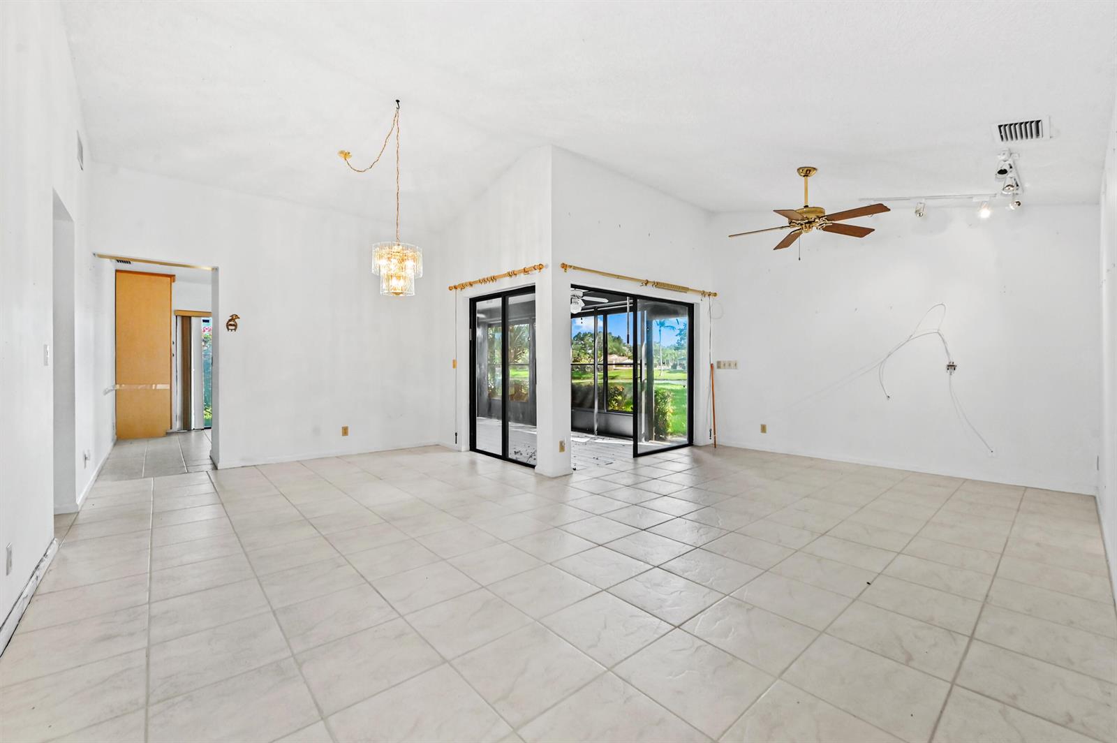 A spacious, empty living room with white walls, tiled floors, a ceiling fan, and sliding doors — 5537 Parkwalk Circle E, Boynton Beach FL 33472, BOYNTON BEACH, FL