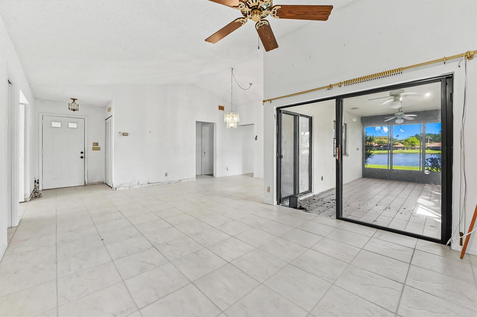 An empty living room features white tile floors, a ceiling fan, and sliding glass doors — 5537 Parkwalk Circle E, Boynton Beach FL 33472, BOYNTON BEACH, FL