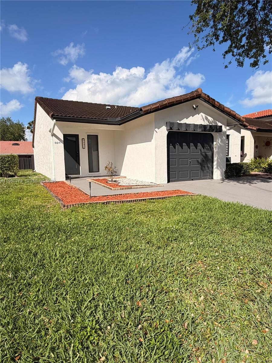 A single-story house with a white stucco exterior, dark roof, and a black garage door — 6641 NW 174th Ter, Hialeah FL 33015, HIALEAH, FL
