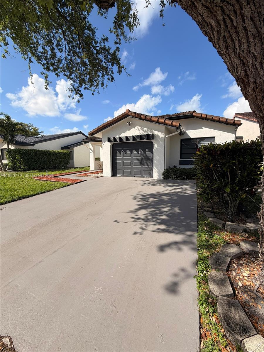 A single-story house with a gray garage door, white stucco walls, and a tiled roof — 6641 NW 174th Ter, Hialeah FL 33015, HIALEAH, FL