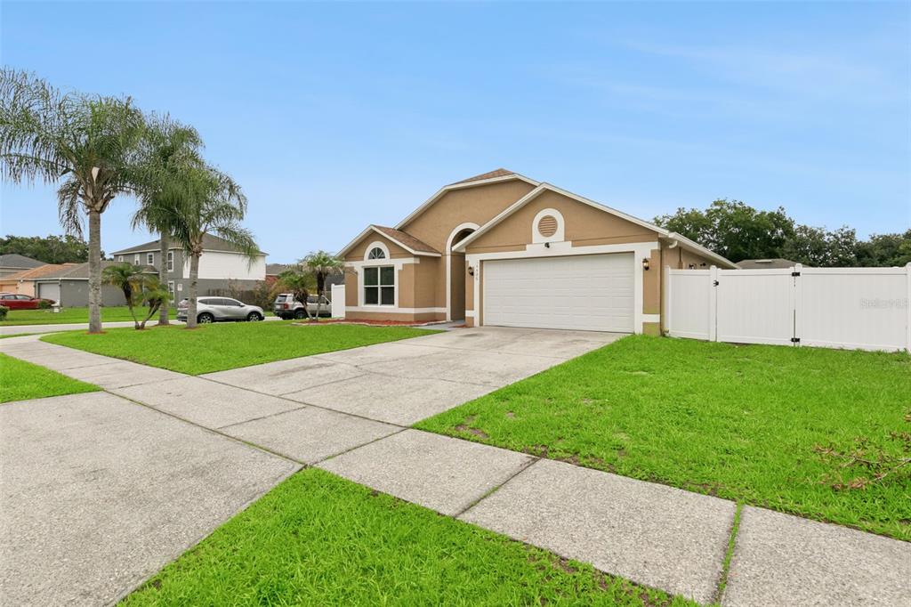 A single-story tan house with a two-car garage and a white vinyl fence — 14426 LAKE PRICE DRIVE, ORLANDO, FL
