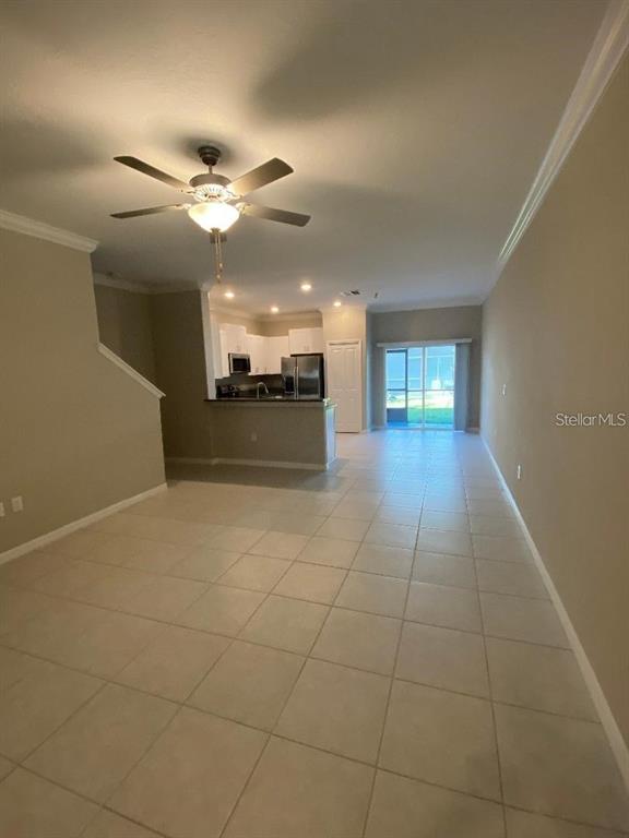 An open-concept living area features tile flooring, a ceiling fan, and a kitchen with appliances — 2179 AZURE VIEW WAY, LUTZ, FL
