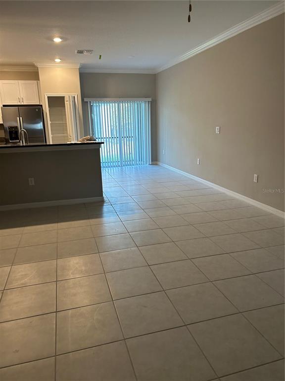 An open-concept kitchen and living area features light tile flooring and a sliding glass door — 2179 AZURE VIEW WAY, LUTZ, FL