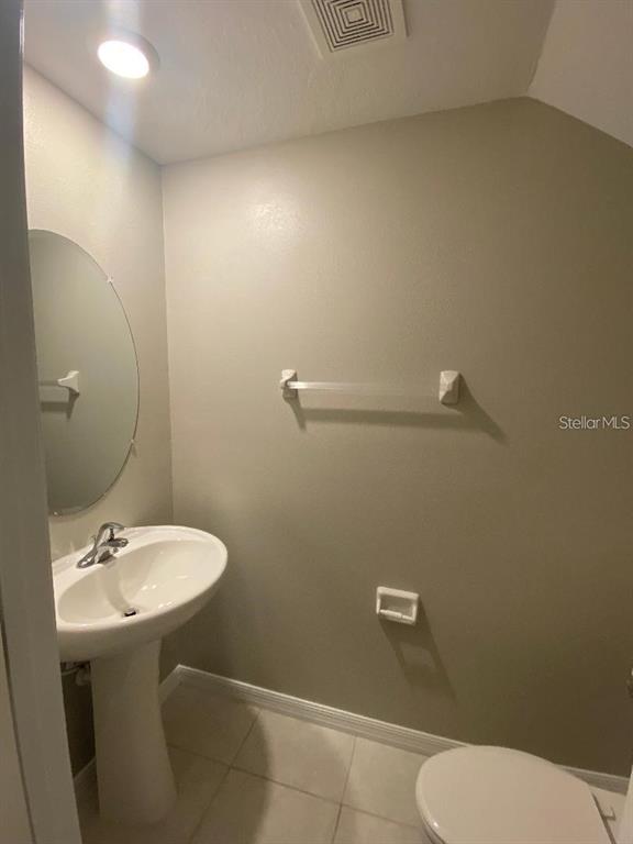 A small bathroom features a pedestal sink, an oval mirror, and a toilet — 2179 AZURE VIEW WAY, LUTZ, FL
