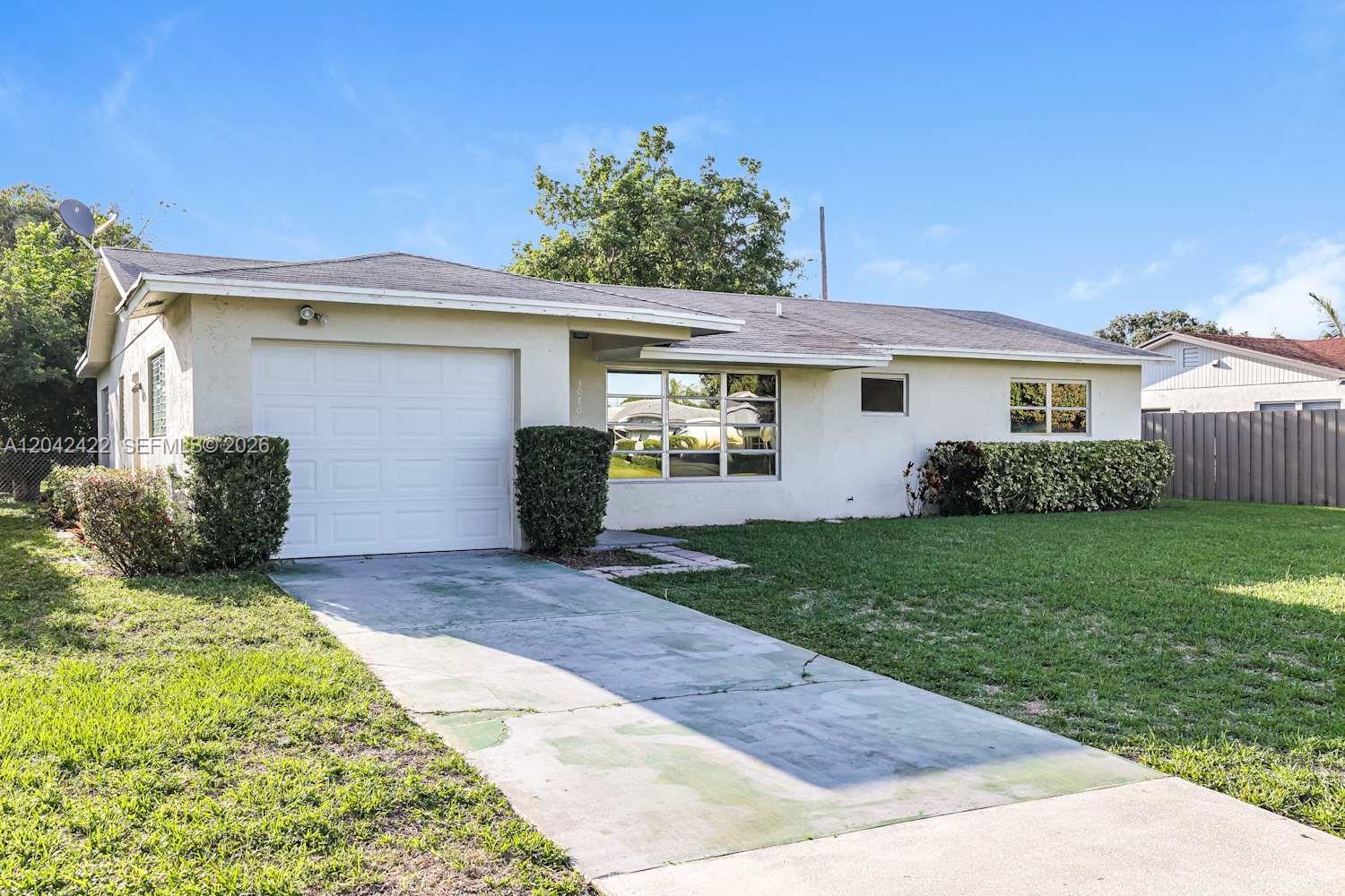 A single-story house with a white stucco exterior, a one-car garage, and a concrete driveway — BOYNTON BEACH, FL