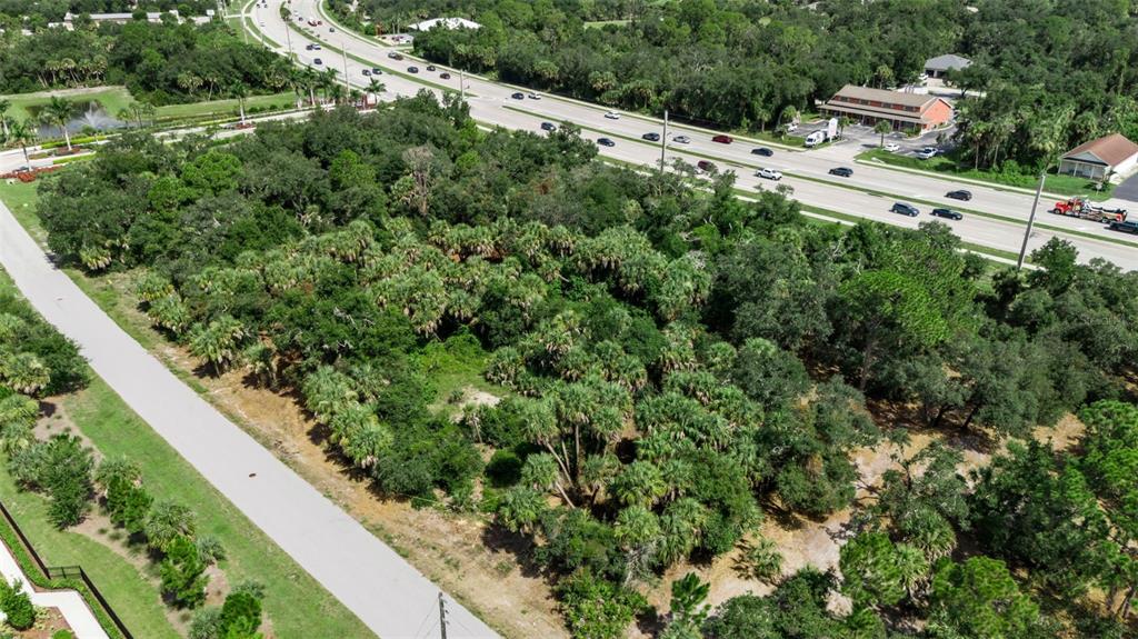 An aerial view shows a wooded, undeveloped lot situated between a road and a highway — 16220 FRANKLIN AVENUE, PORT CHARLOTTE, FL