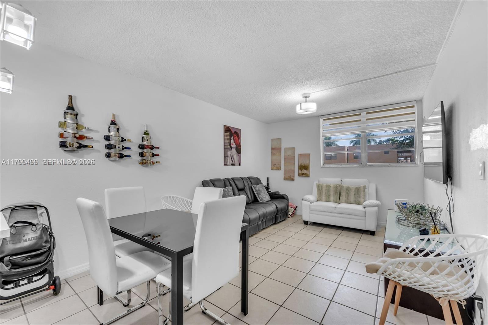 A living and dining area features white tile floors, a black dining set, and two sofas — 4550 NW 9th St # 106E, Miami FL 33126, MIAMI, FL