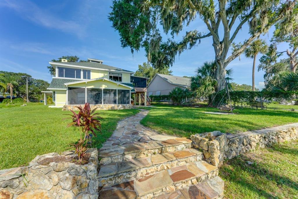 A stone path leads to a yellow two-story house with a screened-in porch and lawn — 900 N HARBOR TERRACE, TAVARES, FL