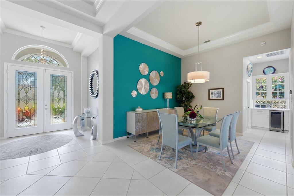 A dining room features a teal accent wall, glass table, and light-colored tile flooring — 7346 WINDEMERE LANE, UNIVERSITY PARK, FL