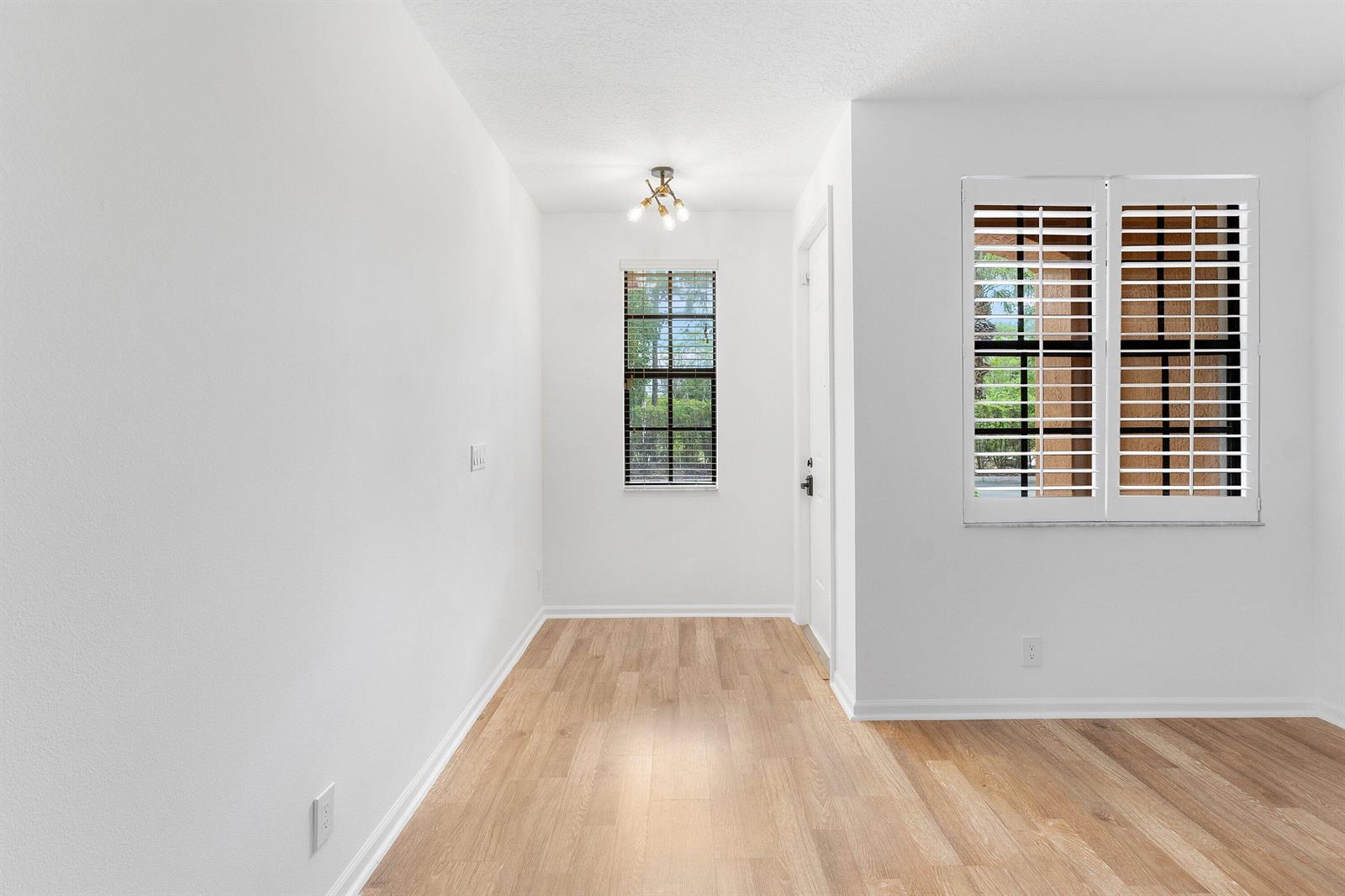 An empty dining area features light wood flooring, white walls, a window, and plantation shutters — 238 E Chrystie Circle, Delray Beach FL 33484, DELRAY BEACH, FL