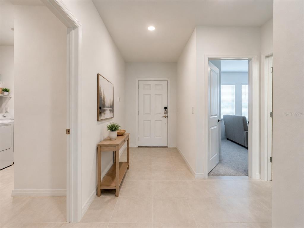 A bright entryway features light tile flooring, a wooden console table, and white walls — 176 JONES FISH CAMP ROAD, EDGEWATER, FL