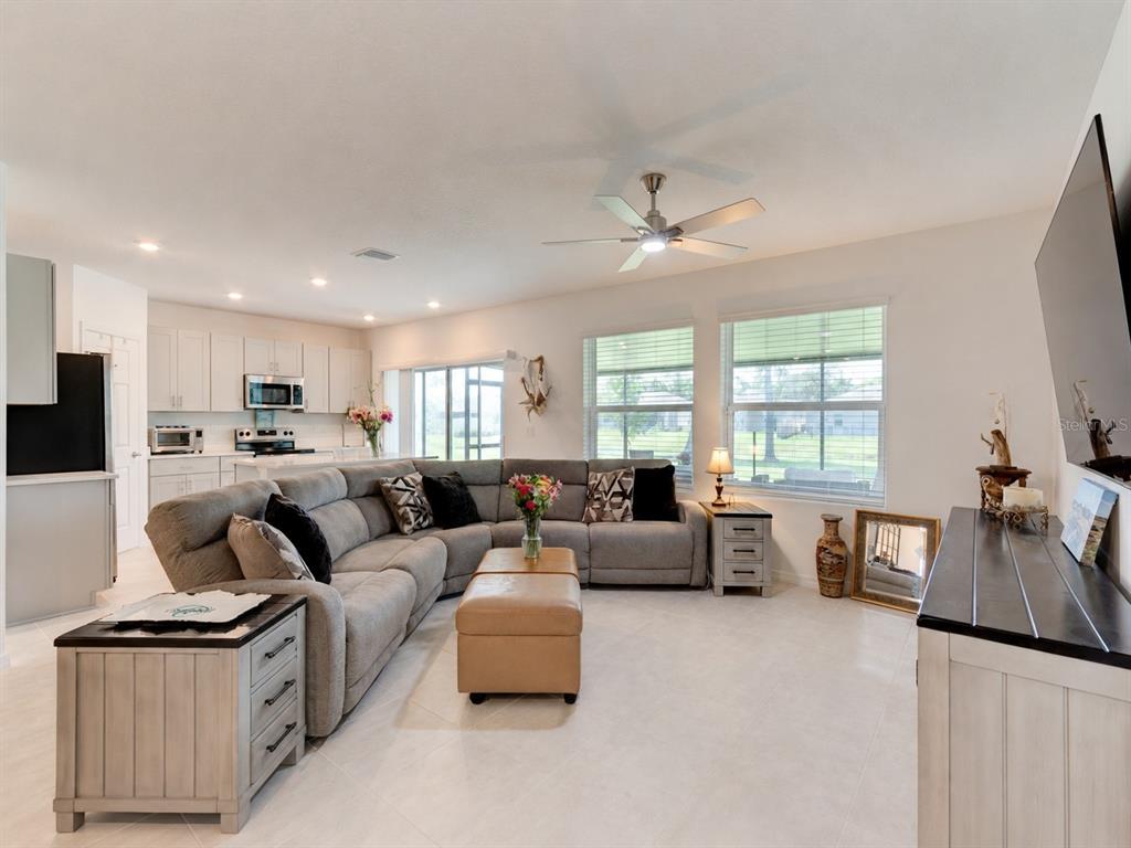 A living room with a large gray sectional sofa, light tile floors, and an open kitchen — 176 JONES FISH CAMP ROAD, EDGEWATER, FL