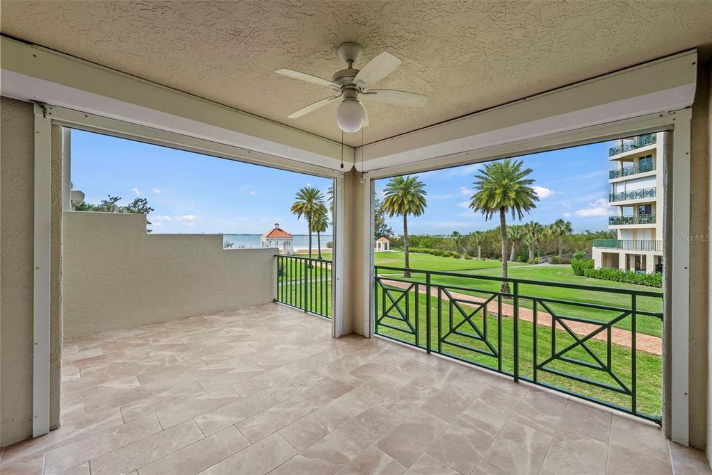 A covered balcony with tile flooring, a ceiling fan, and green railings overlooking a lawn — 4780 DOLPHIN CAY LANE S UNIT 109, ST PETERSBURG, FL