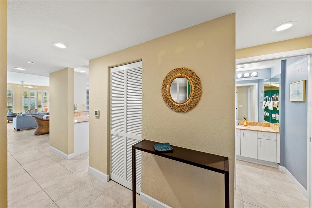 A hallway with a console table, a round mirror, and a view into a bathroom — 4780 DOLPHIN CAY LANE S UNIT 109, ST PETERSBURG, FL