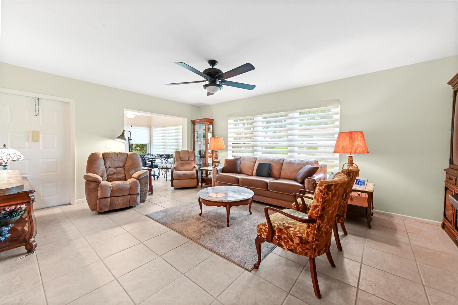 A living room features tile flooring, a ceiling fan, a sofa, and several armchairs — 14080 Nesting Way # A, Delray Beach FL 33484, DELRAY BEACH, FL