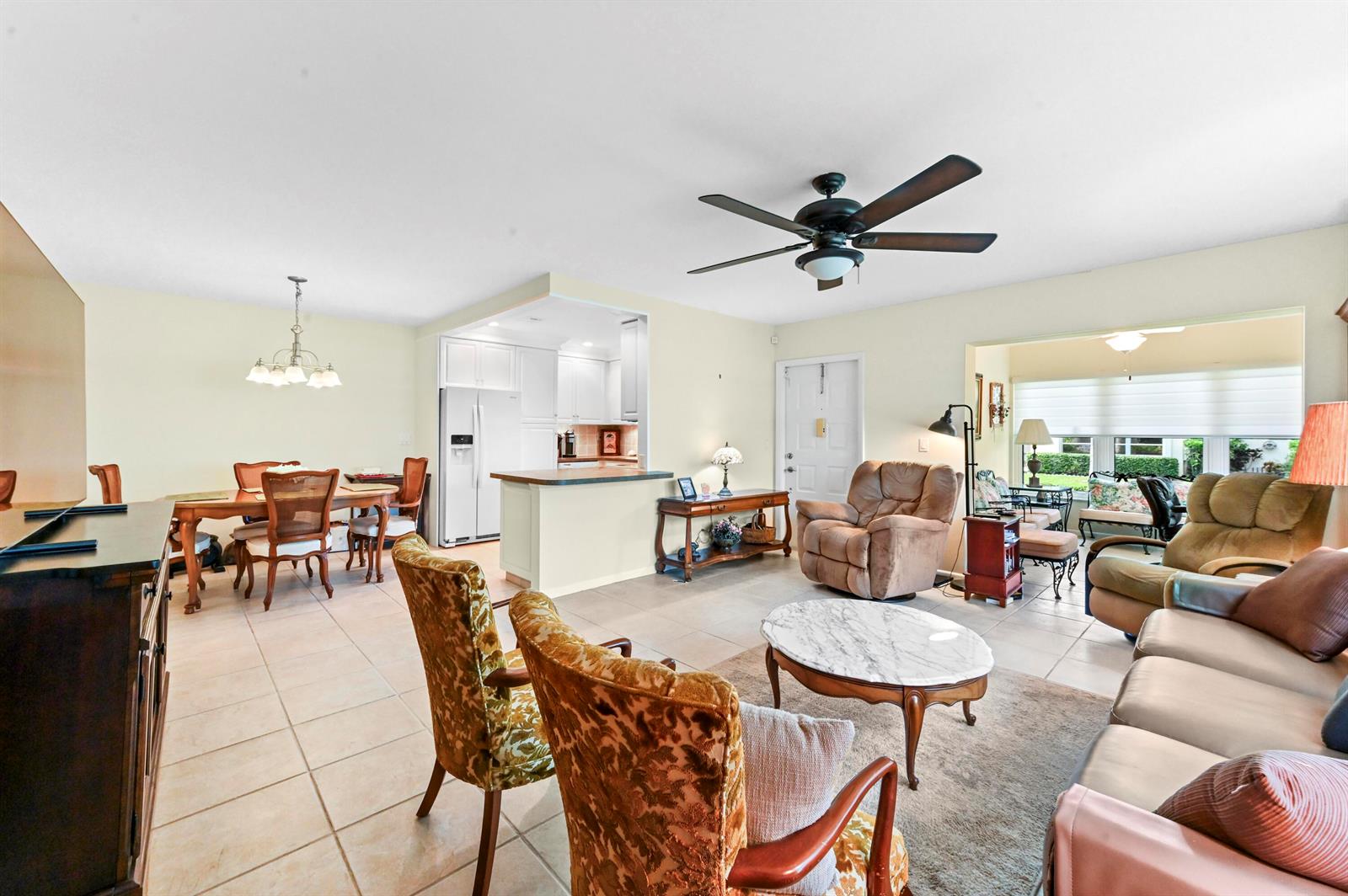 An open-concept living and dining area features tile flooring, a ceiling fan, and neutral walls — 14080 Nesting Way # A, Delray Beach FL 33484, DELRAY BEACH, FL