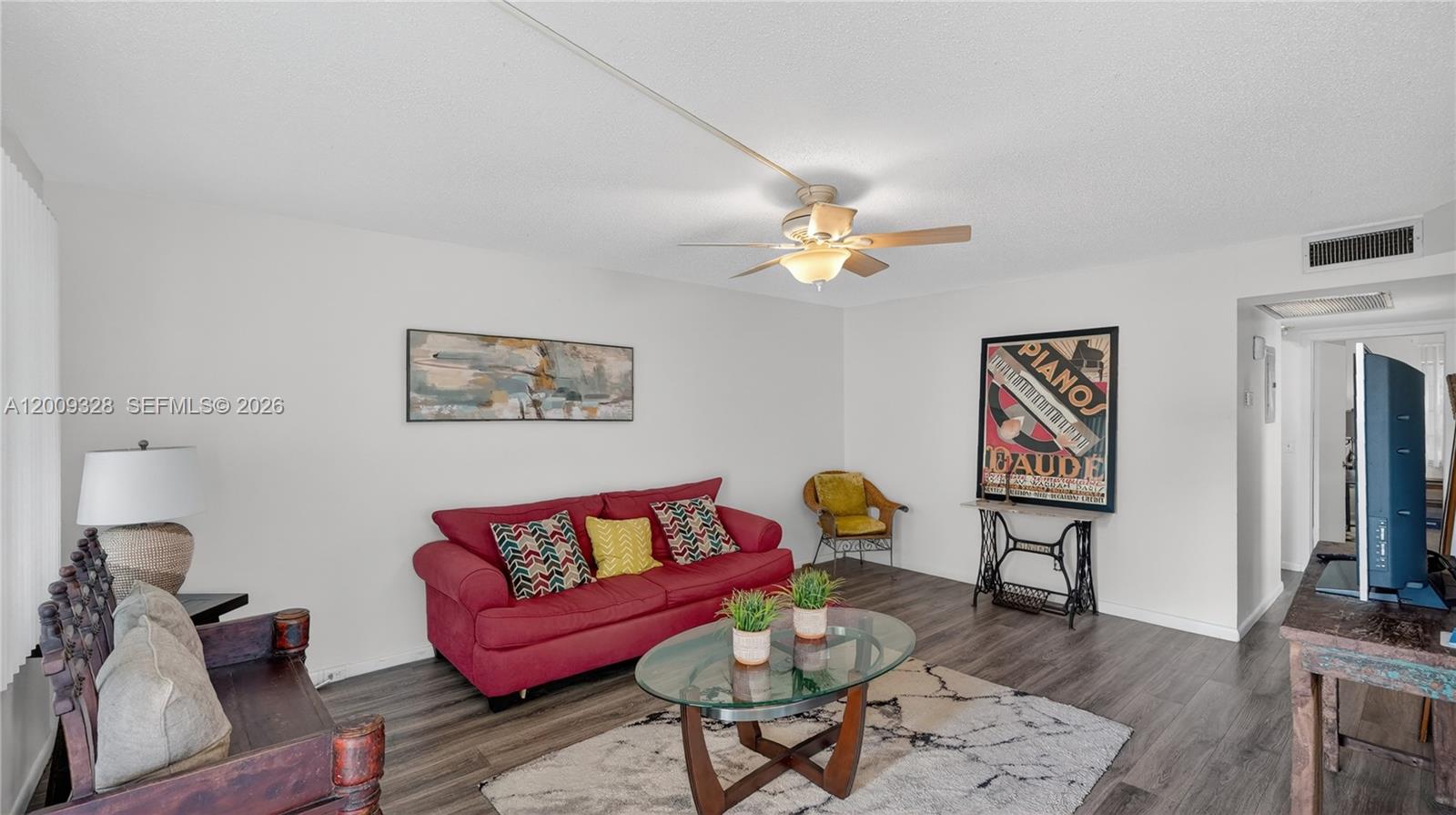 A living room features a red sofa, glass coffee table, and dark wood-look flooring — 438 Mansfield K # 438, Boca Raton FL 33434, BOCA RATON, FL