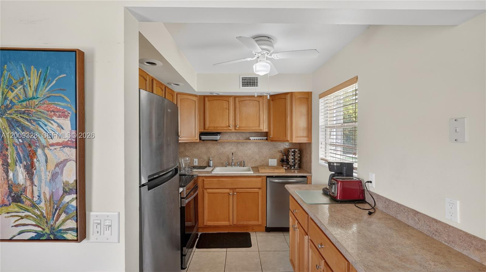 A kitchen features wooden cabinets, stainless steel appliances, and a beige countertop — 438 Mansfield K # 438, Boca Raton FL 33434, BOCA RATON, FL