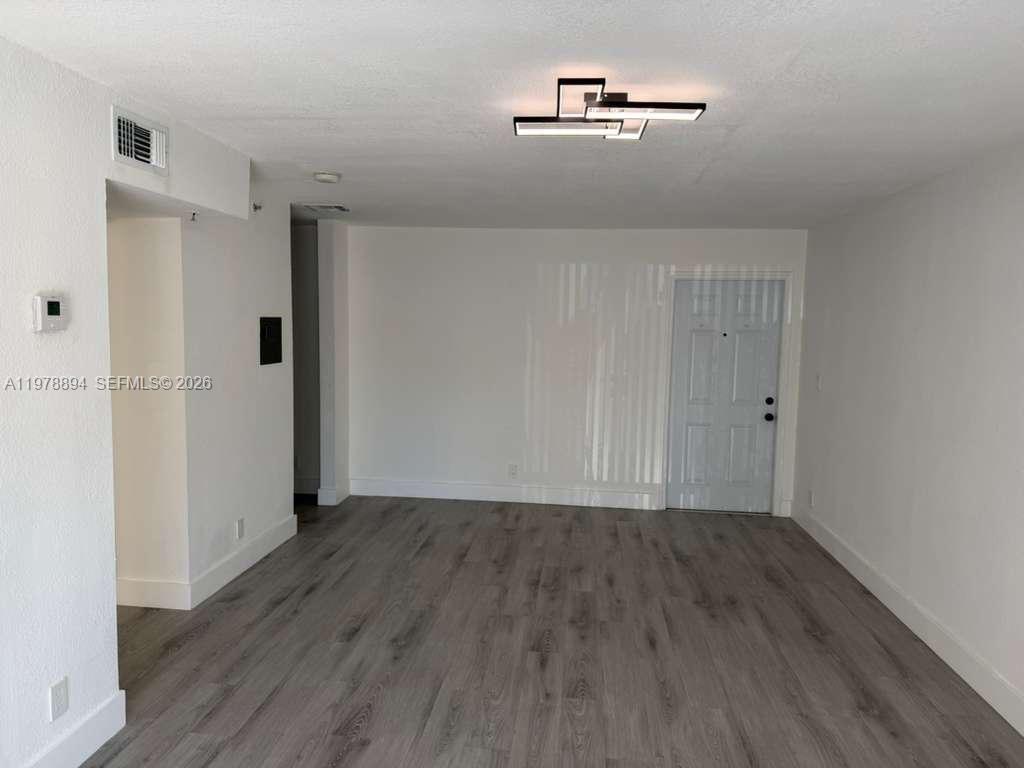 An empty room features white walls, gray wood-look flooring, and a modern ceiling light fixture — 4271 NW 5th St # 129, Plantation FL 33317, PLANTATION, FL