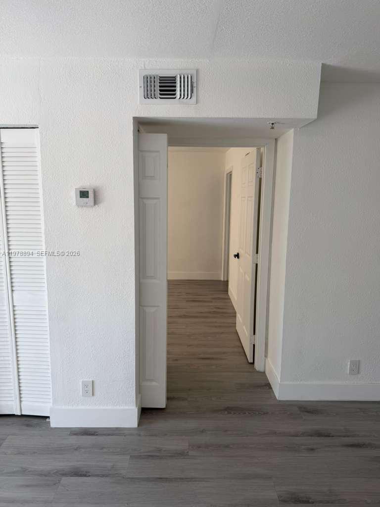 A doorway leads from a room with white walls and wood-look flooring to a hallway — 4271 NW 5th St # 129, Plantation FL 33317, PLANTATION, FL