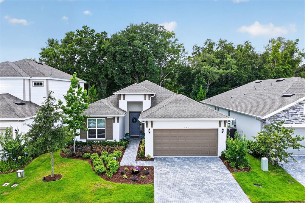 A single-story suburban house with a gray shingled roof, brown garage door, and paved driveway — 2289 SIRENA LANE, MOUNT DORA, FL