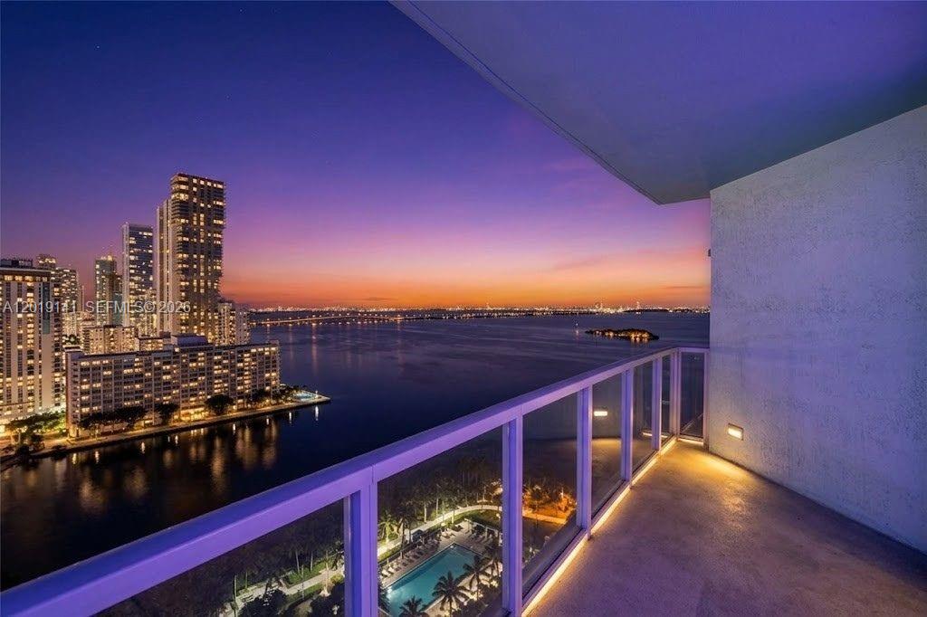 A balcony overlooks a city skyline, a bay, and a swimming pool at sunset — 1900 N Bayshore Dr # 2204, Miami FL 33132, MIAMI, FL