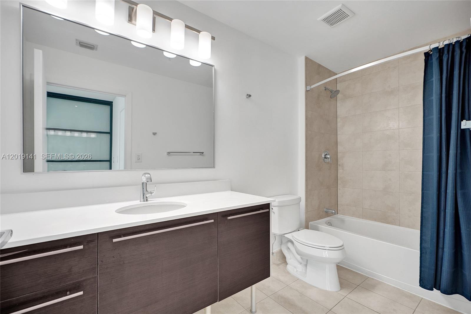 A bathroom features a dark wood vanity, a large mirror, and a tiled shower-tub combination — 1900 N Bayshore Dr # 2204, Miami FL 33132, MIAMI, FL