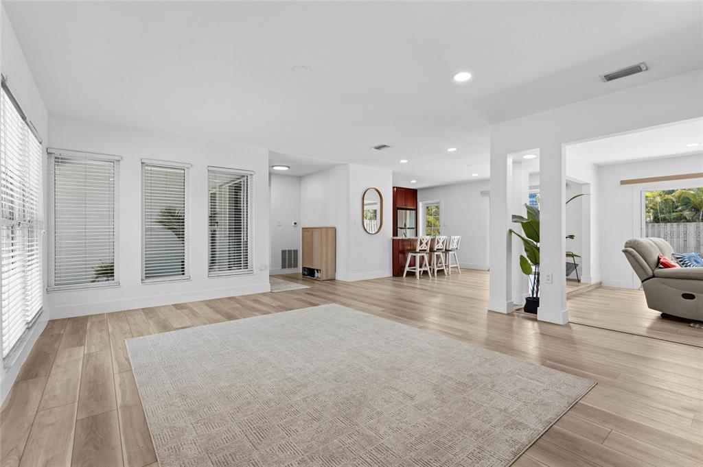 A bright, open-concept living area features light wood-look flooring, white walls, and a large rug — 138 HOLLY AVENUE, SARASOTA, FL