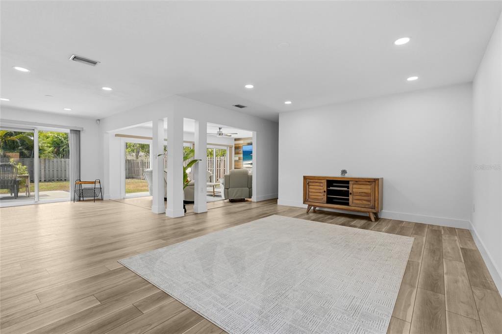 A bright living room features light wood-look flooring, recessed lighting, and a wooden media console — 138 HOLLY AVENUE, SARASOTA, FL
