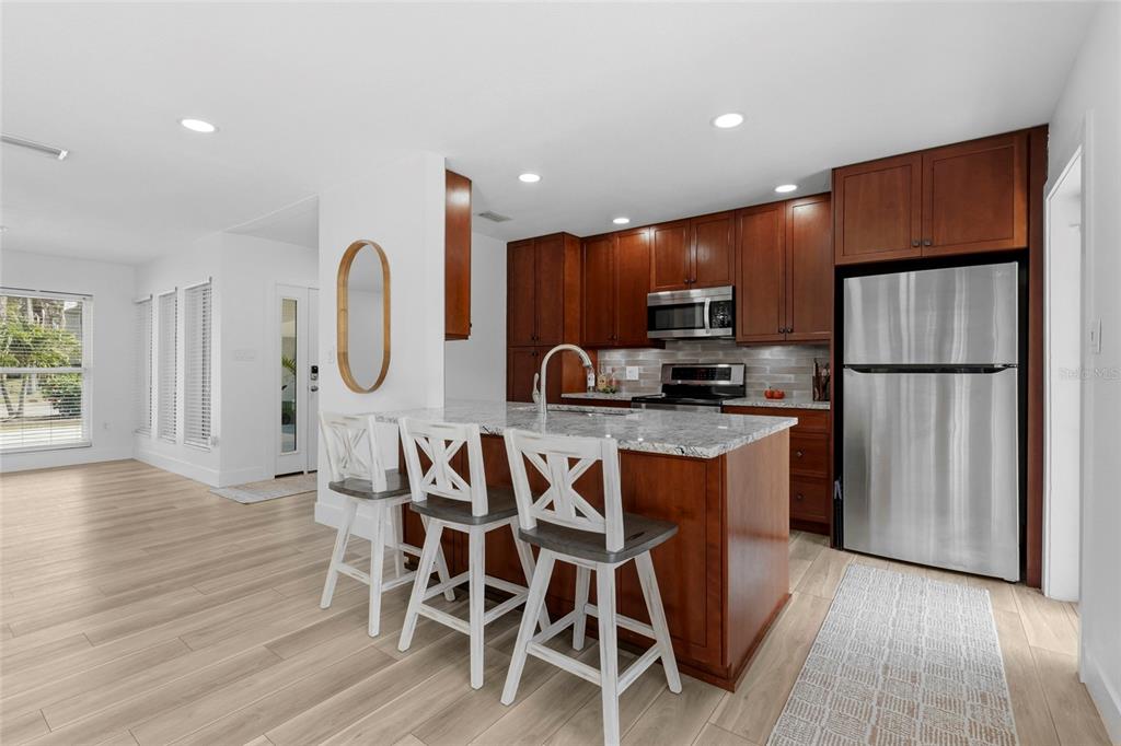 A kitchen with wood cabinets, granite countertops, a center island with stools, and stainless appliances — 138 HOLLY AVENUE, SARASOTA, FL
