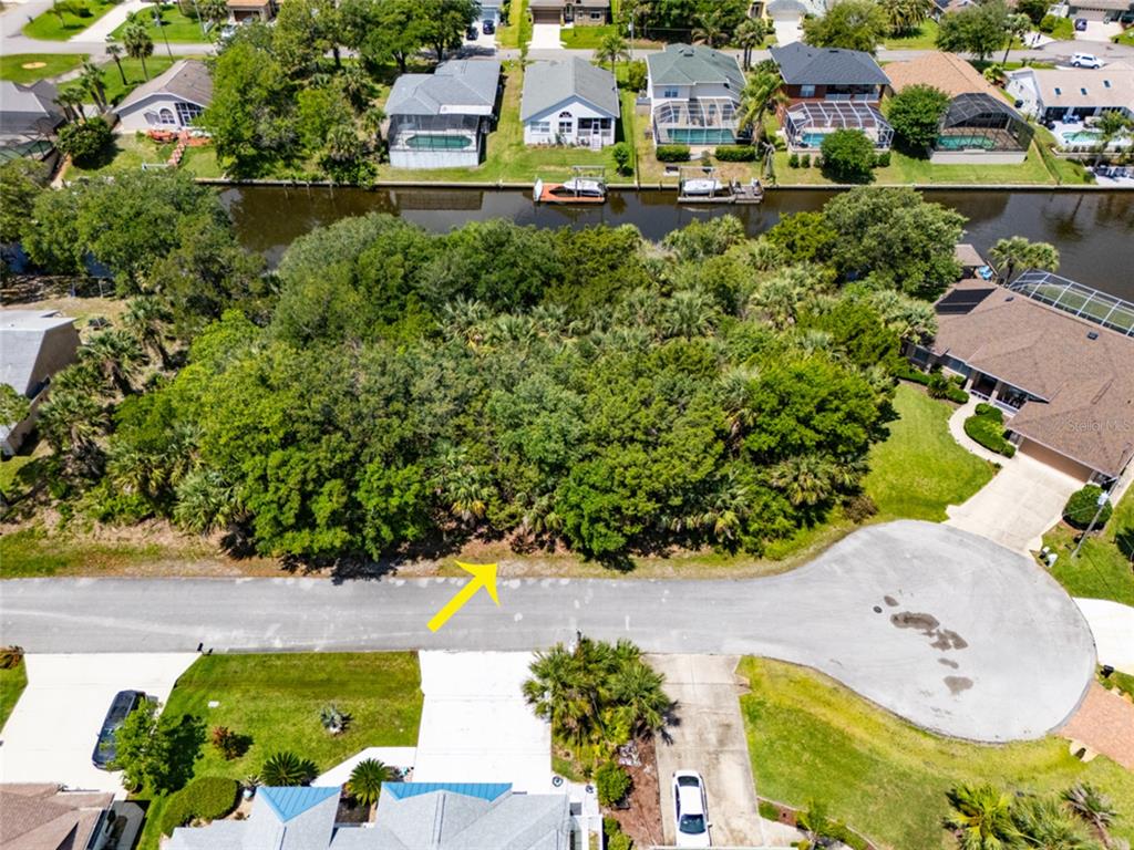 An aerial view shows a vacant, wooded residential lot situated between a cul-de-sac and a canal — 21 CORNING COURT, PALM COAST, FL