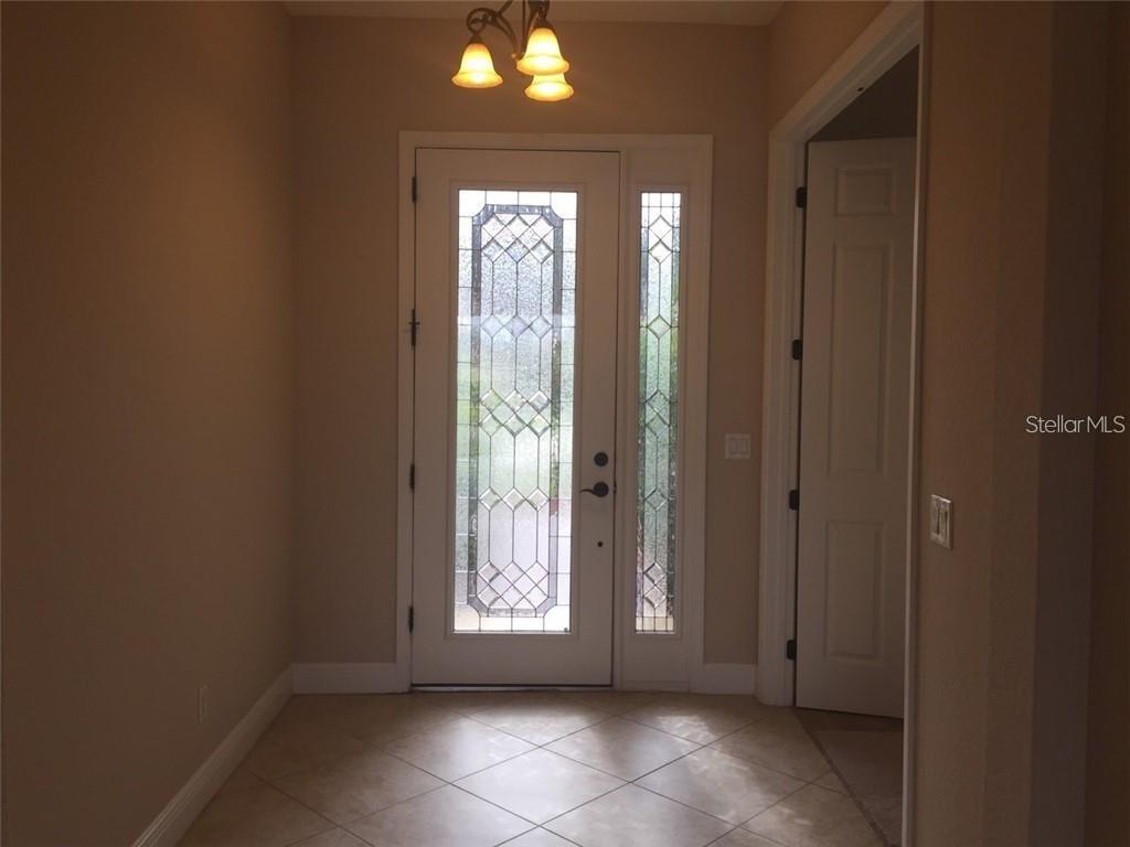 An entryway features a tiled floor, a decorative glass front door, and a light fixture — 5570 ROCK DOVE DRIVE, SARASOTA, FL